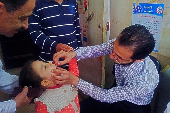Resident administering oral polio vaccine to a 