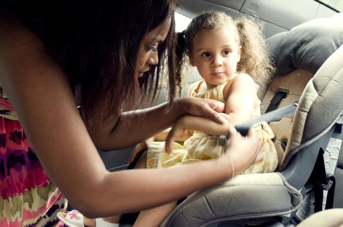 Mother putting daughter in seat belt